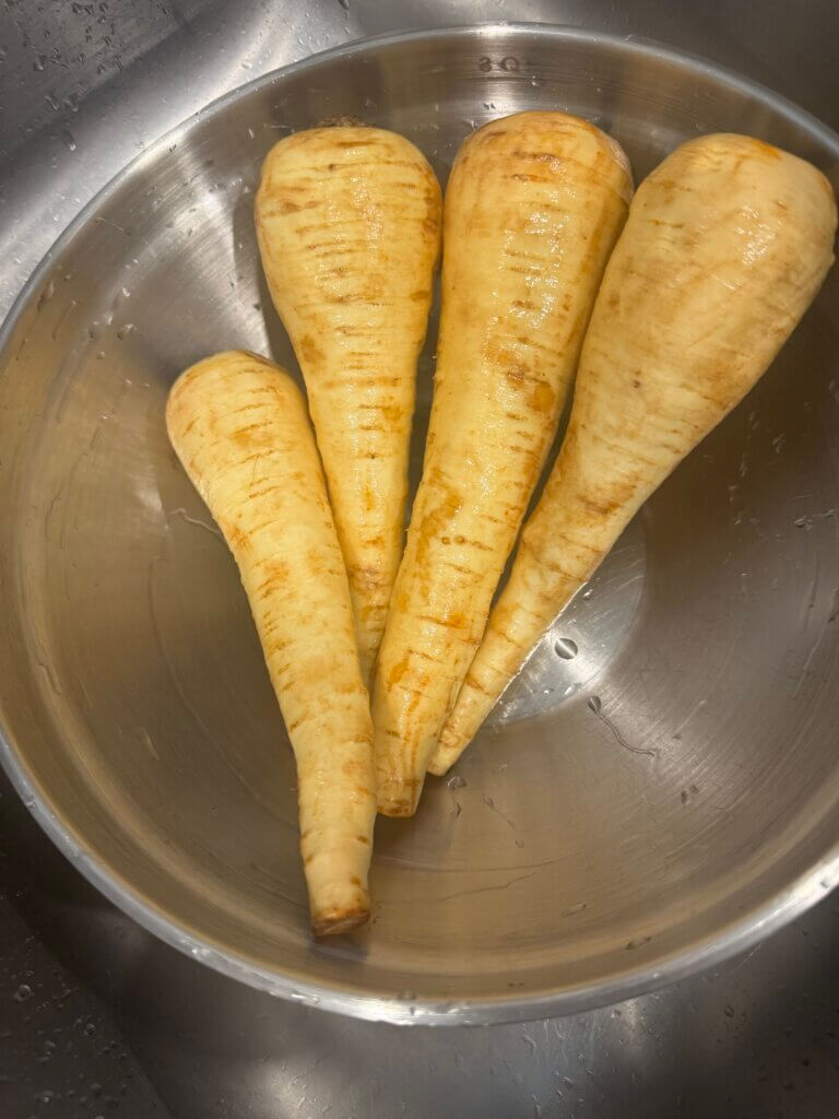 Raw parsnips in a stainless steel bowl, ready to cook or roast.